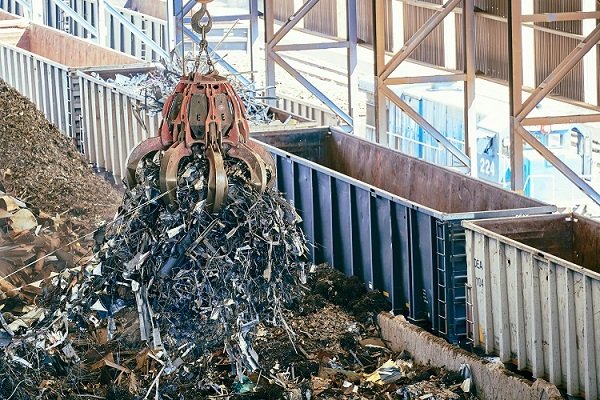 A large industrial grabber lifting a huge load of scrap metal for recycling and waste services